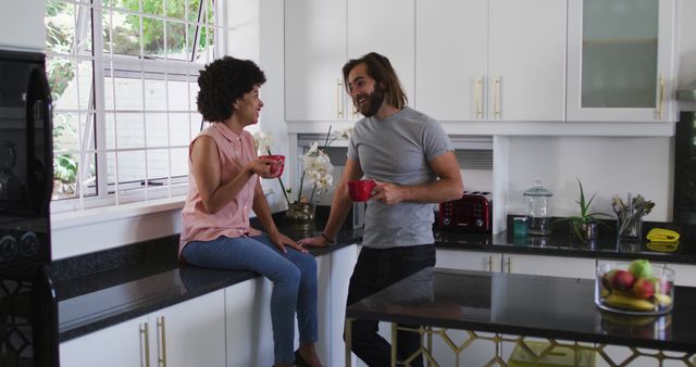 Biracial couple holding coffee cup talking to each other in the kitchen at home - Download Free Stock Photos Pikwizard.com