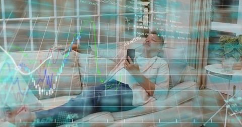 Reclining man monitoring stock market charts on smartphone, relaxing on home sofa