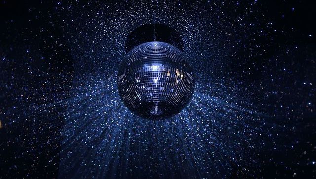Blue mirrored disco ball casting radiant starburst beams, sparkling haze, club nightlife