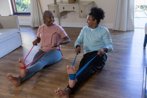 Intergenerational home workout exercising with resistance bands senior woman and young man