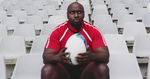Rugby Player in Stadium Holding Ball with Pensive Look