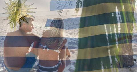 Couple relaxing on tropical beach with uruguayan flag overlay and palm silhouette