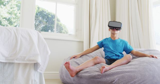 Caucasian boy wearing vr headset while sitting on the bean bag at home. entertainment technology concept