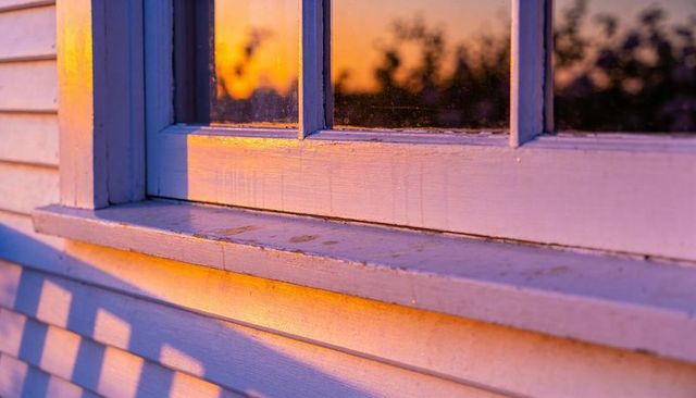 Sunset light glowing on weathered wooden window sill with peeling paint