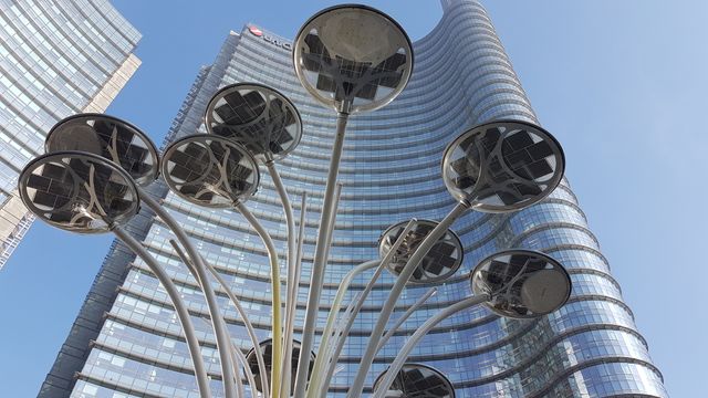 Modern art installation displayed in front of towering urban skyscrapers with a clear blue sky. This is perfect for use in architectural presentations, urban design projects, city planning promos, and contemporary art features.