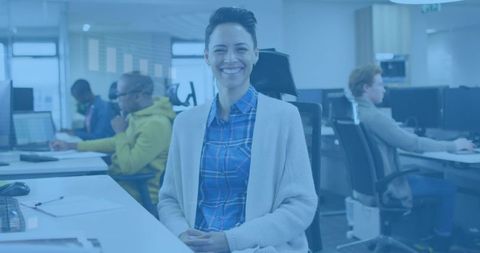 Smiling woman in plaid shirt and cardigan in modern open-plan office, friendly teamwork