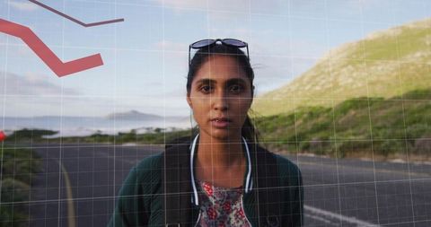 Young indian woman standing on coastal road with backpack and sunglasses