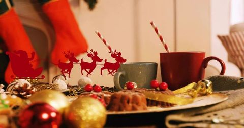 Cozy christmas table with bundt cakes, festive mugs and santa sleigh cutout