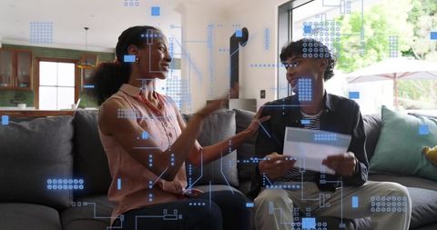 Mother and Teen Reviewing Documents on Couch with Futuristic HUD Overlay for Home Finances