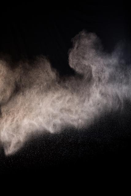Dust powder splashing on black background creating a dramatic and dynamic effect. Ideal for use in artistic projects, backgrounds, textures, or as a visual element in presentations and designs.