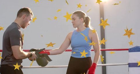 Female boxer training with coach in ring, red hand wraps, focused determined athlete