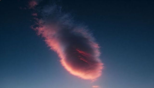 Glowing pink-rimmed lenticular cloud drifting over indigo twilight sky minimalist atmosphere