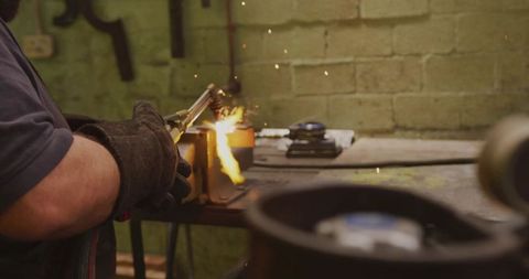 Metalworker Using Torch for Precision Heating in Workshop