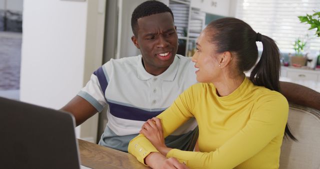 Image of happy diverse couple watching laptop together and smiling sitting in kitchen - Download Free Stock Photos Pikwizard.com