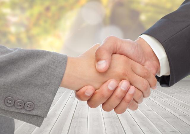 Digital composite image of business executives shaking hands against wooden plank