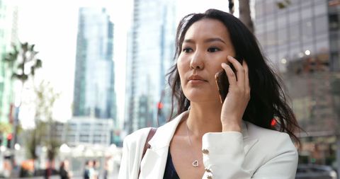 Confident Asian Businesswoman Walking in City Talking on Mobile Phone