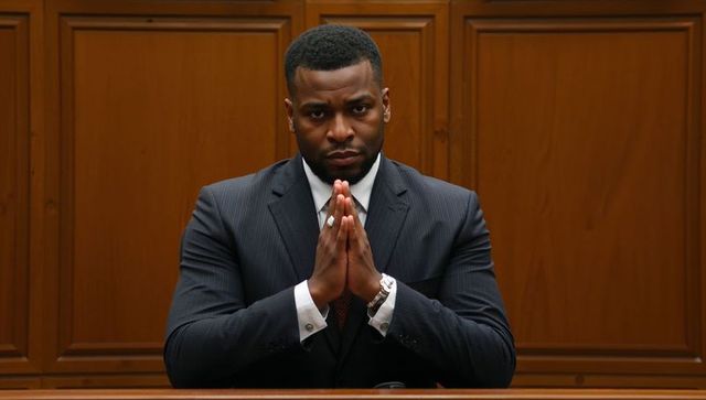 Contemplating courtroom attorney holding fingertips together at wooden witness bench