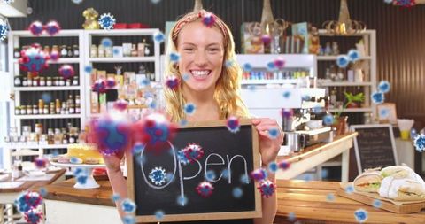 Cafeteria open amid pandemic: smiling barista holding open sign