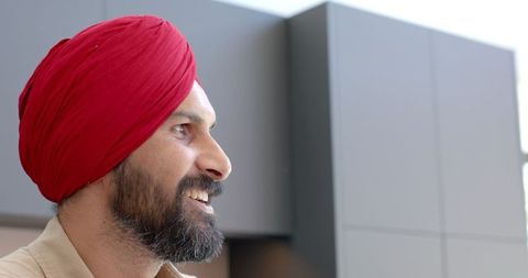 Smiling man in red turban enjoying relaxation indoors
