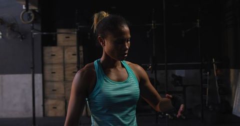 Focused athletic woman unwrapping hands after boxing training