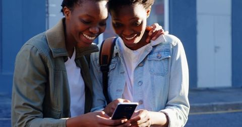 Joyful Twin Sisters Bonding with Phone Outdoors - Download Free Stock Images Pikwizard.com