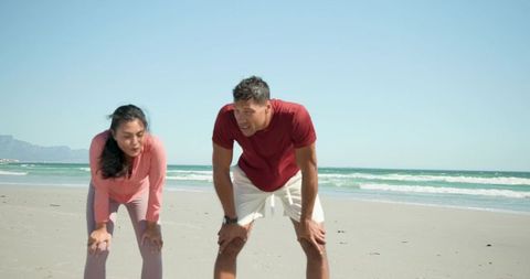 Couple catching breath after beach workout showing fitness tracker and ocean recovery