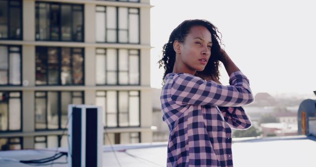 Young Woman Adjusting Hair on Urban Rooftop - Download Free Stock Images Pikwizard.com