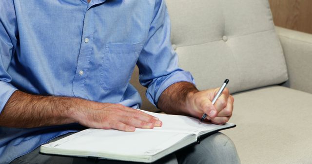 Man writing in notebook on sofa - Download Free Stock Images Pikwizard.com