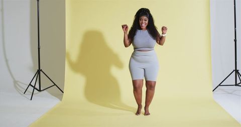 Confident african american woman in activewear on yellow backdrop