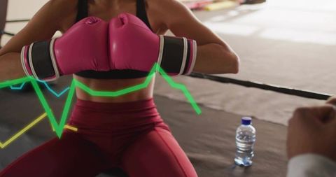 Woman boxer resting in ring wearing pink gloves with neon performance data overlay