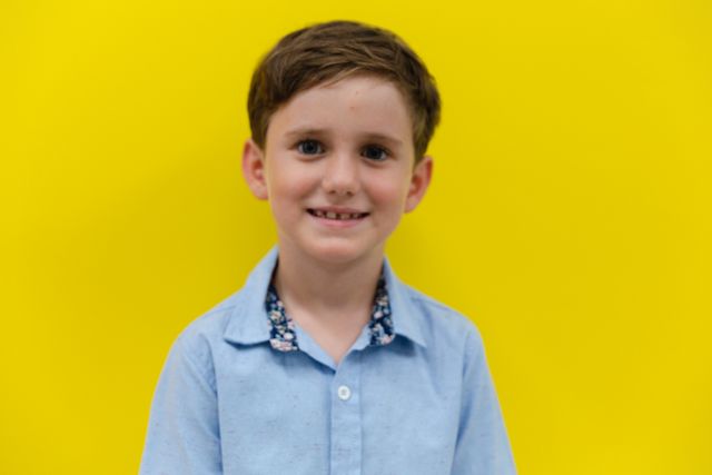 Portrait of smiling cute caucasian elementary schoolboy against vibrant yellow background - Download Free Stock Photos Pikwizard.com