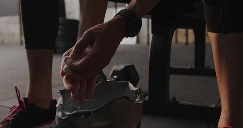 Focused female athlete applying chalk in weightlifting gym