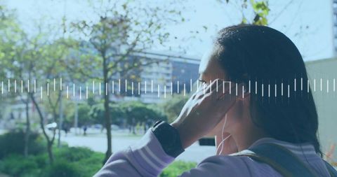 Adjusting earbud in urban park with smartwatch and backpack, audio waveform overlay