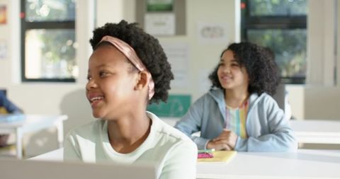 African American Teen Girls Smiling and Learning in Sunlit Classroom with Laptop