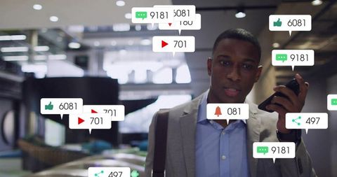 Businessman checking mobile notifications in modern office lobby with social engagement icons