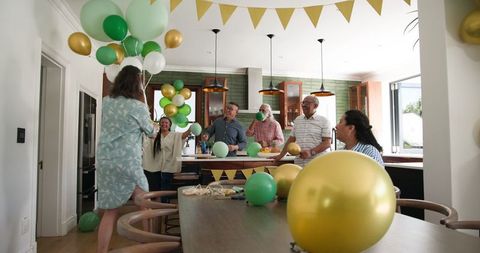 Senior friends enjoying party preparation with balloons and decor