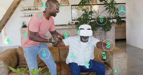 Adult son assisting senior wearing vr headset reaching from couch in modern open-plan home