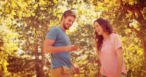 Young Couple Laughing at Smartphone in Sunny Autumn Park - Download Free Stock Images Pikwizard.com