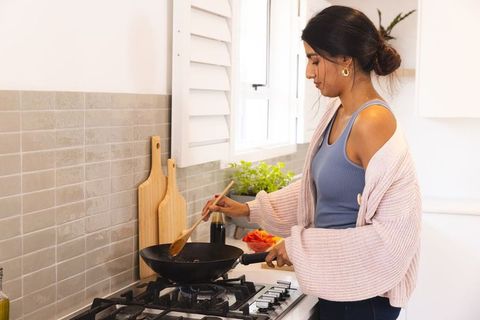 Asian Woman Cooking on Gas Stove in Cozy Home Kitchen