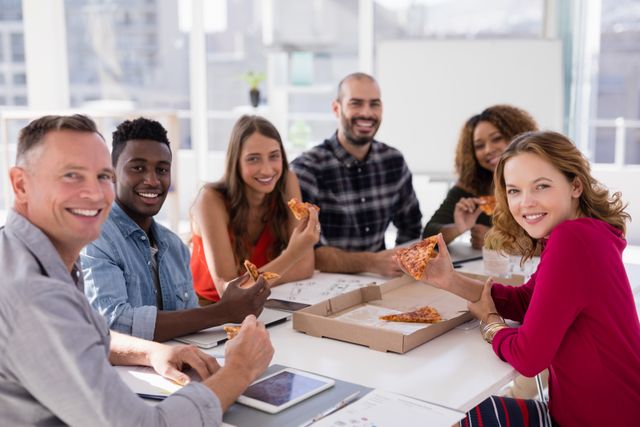Group of diverse colleagues enjoying pizza during a casual office meeting. Perfect for illustrating teamwork, corporate culture, and work-life balance. Ideal for use in business presentations, corporate websites, and promotional materials highlighting a positive work environment.