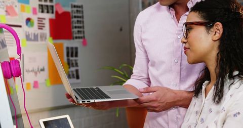 Business Professionals Collaborating Over Laptop in Creative Office
