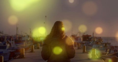 Woman on harbor pier at sunset viewing tranquil horizon