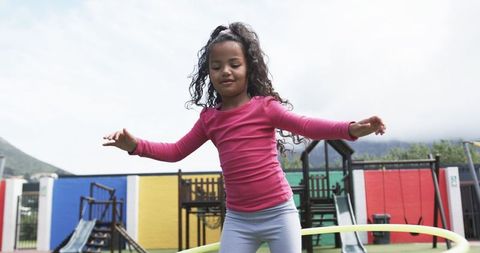 Young Girl Hula Hooping with Delight in Playground Setting