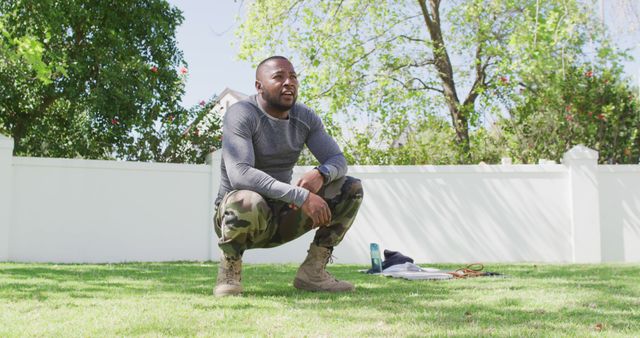 Tired african american male soldier exercising in a sunny garden. Patriotism, army and returning home concept.