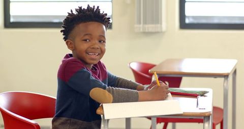 Smiling African American Boy Writing in Classroom