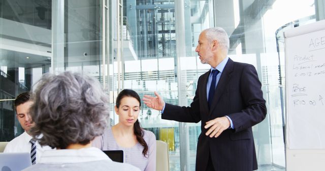 Senior Businessman Presenting Data to Colleagues in Modern Office - Download Free Stock Images Pikwizard.com