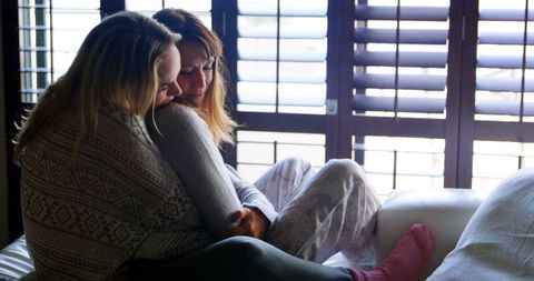 Lesbian Couple Embracing on Bed in Sunlit Room
