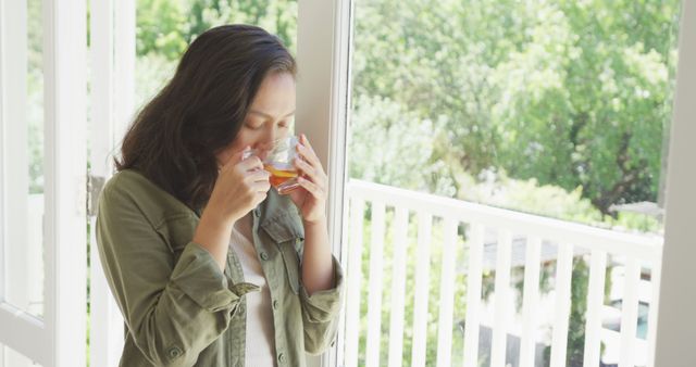 Young Woman Enjoying Hot Beverage by Sunlit Window - Download Free Stock Images Pikwizard.com