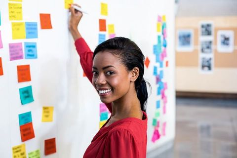 Smiling Woman Engaged in Creative Brainstorming with Sticky Notes