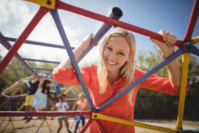 Portrait of happy teacher looking through dome climber at school playground